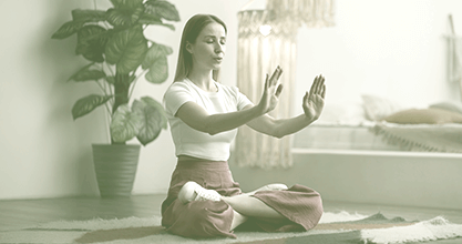 Mulher sentada em posição de meditação e mãos estendidas à frente